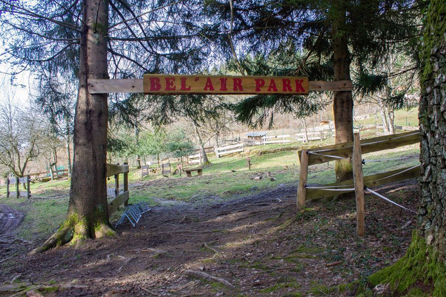 Un panneau avec l'inscription "Bel'Air Park" accroché entre deux sapins