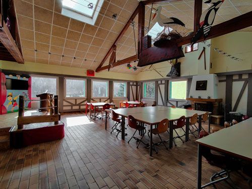 Salle à manger avec des tables, chaises dans une pièce avec des boiseries dans un style alsacien